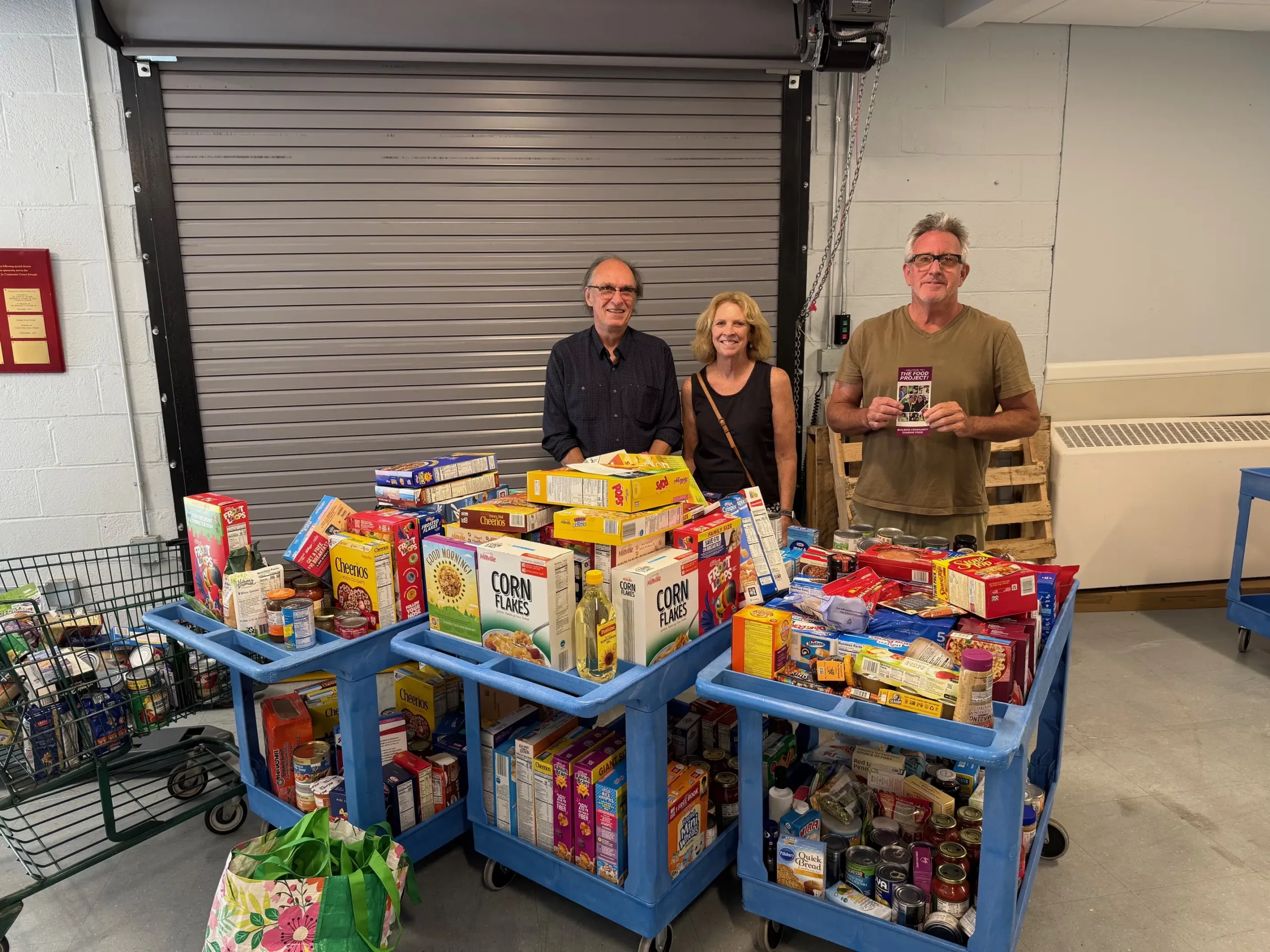 Volunteers stand behind carts filled with donated nonperishable food at the Newport County Neighborhood Food Project after a Collection Day.