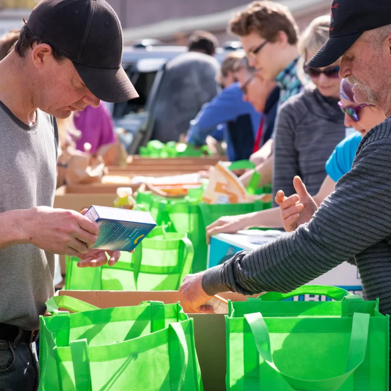 Volunteers Sorting Donated Food In Green Bags