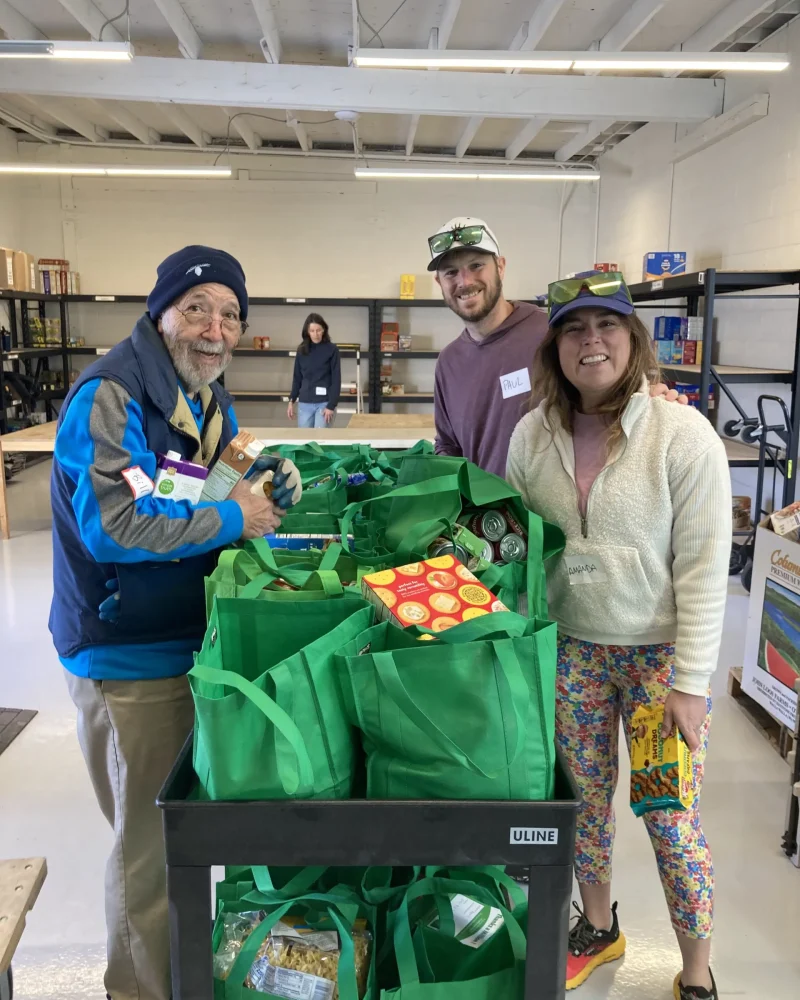 Food Project volunteers standing with green bags full of donated food at pantry collection site