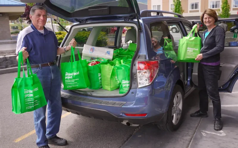 Food Project volunteers unloading green donation bags from vehicle on pickup day