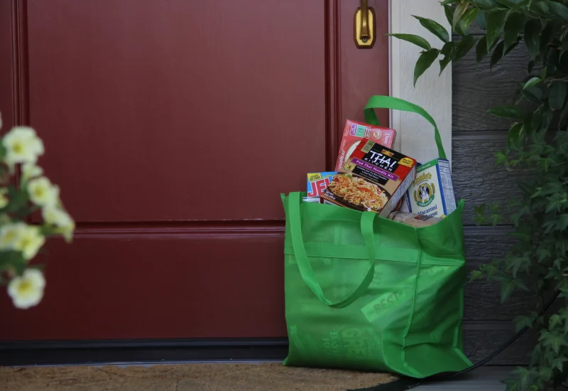 Food donor's filled green donation bag outside for pickup on collection day
