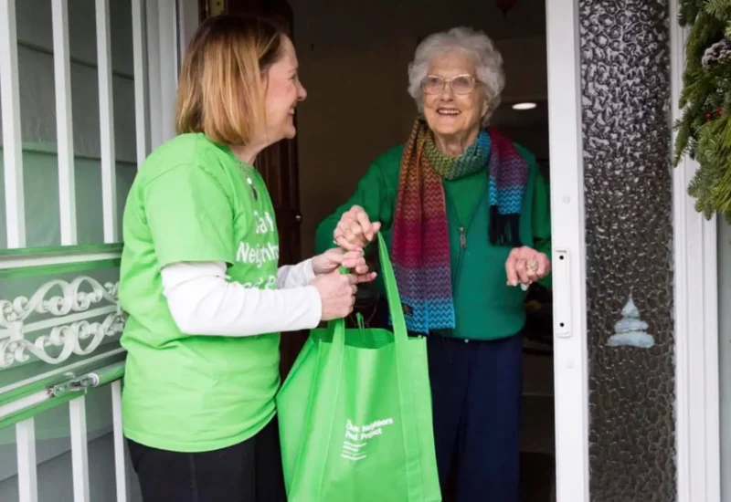 Neighborhood Food Project volunteer delivering green bag to food donor at front door