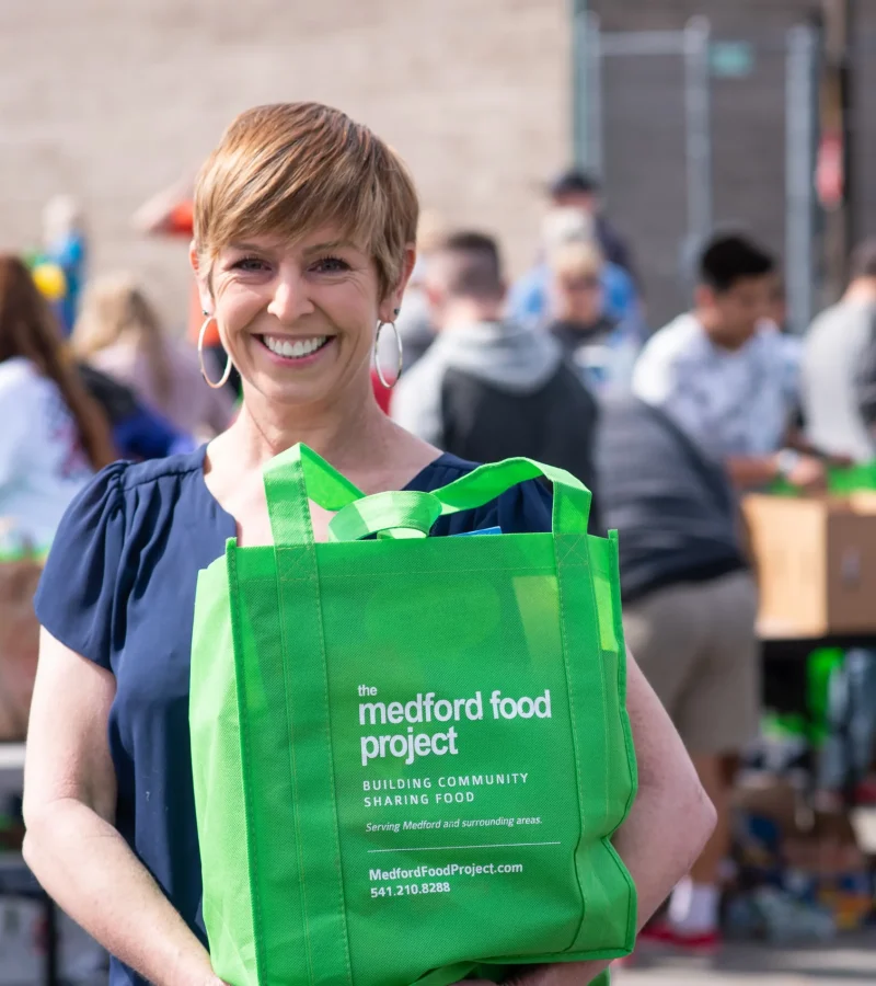 Volunteer holding green Food Project bag during neighborhood food collection day